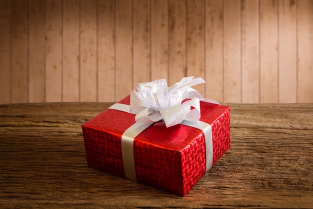 Rote Geschenkbox mit silbernem Band auf Holztisch mit Mehrfarben-bokeh Hintergrund