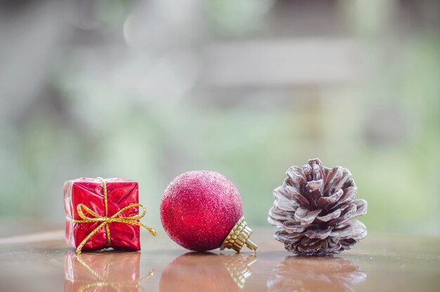 Rote Geschenkbox, rote Kugel und Kieferkegel für Weihnachtsdekorationshintergrund