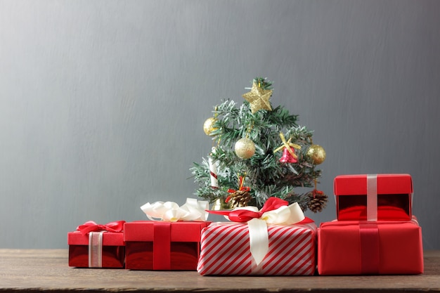 Rote Geschenkboxen und Weihnachtsbaum auf hölzernem Hintergrund.