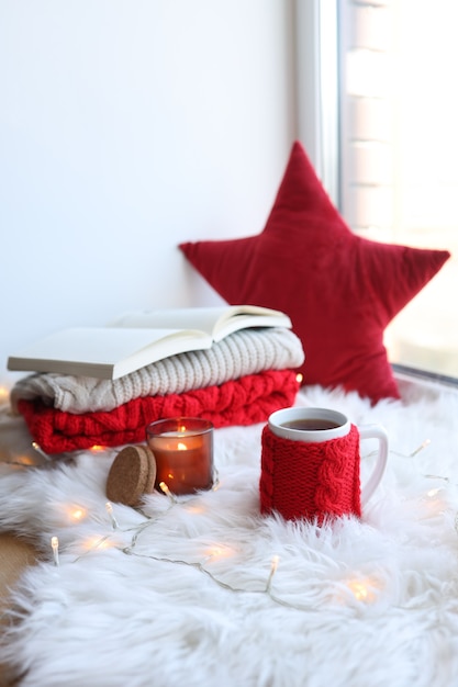 Rote gestrickte Tasse mit einem Getränk auf einem Weihnachtshintergrund