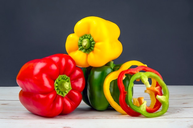 Rote grüne gelbe Paprika ganz und auf schwarzem Steintisch geschnitten