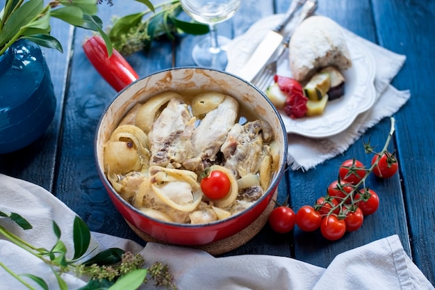 rote Gusseisenbratpfanne mit Huhn auf dem Tisch.