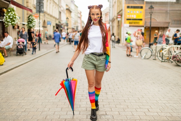 Rote Haarfrau mit lgbt Flagge auf ihrem Gesicht mit Regenbogenschirm