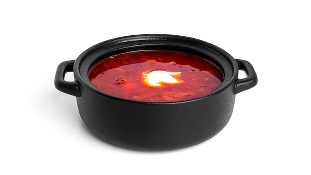 Foto rote, heiße borscht - rübensuppe mit saurer sahne im schwarzen topf lokalisiert auf weiß.