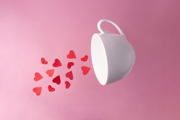 Rote Herzen fliegen aus einer weißen Tasse, Nahaufnahme. Valentinstag.