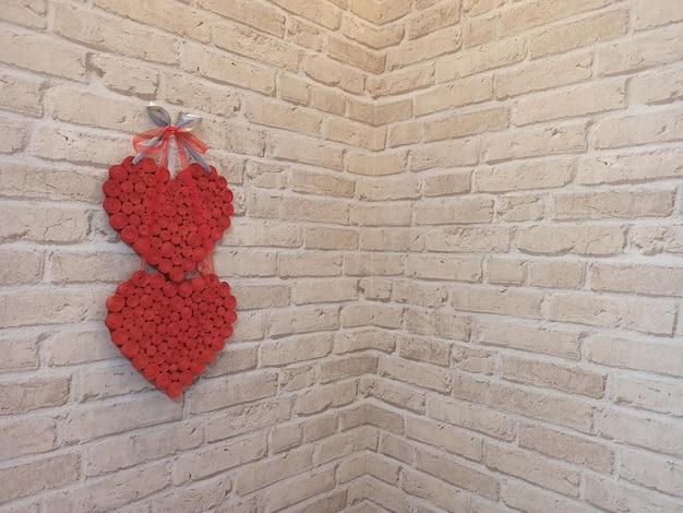 Rote Herzen hängen an der Ziegelsteinwand in der Nähe der Ecke des Zimmers Symbol der Liebe Liebhaber Symbol