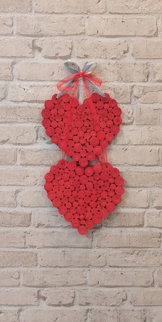 Rote Herzen hängen an einer Ziegelsteinmauer, ein Symbol der Liebe, ein Symbol der Liebenden.