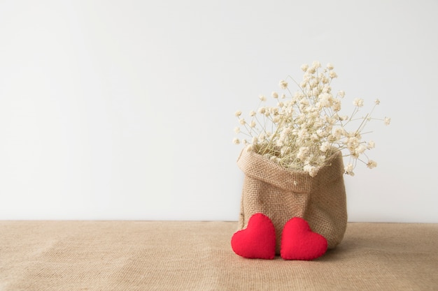 Rote Herzen mit Blumen in der Sacktasche mit Kopienraum auf weißem Hintergrund