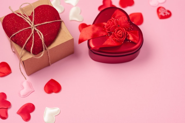 Rote herzen mit einem geschenk zum valentinstag auf einem schönen rosa hintergrund. herzanhänger.