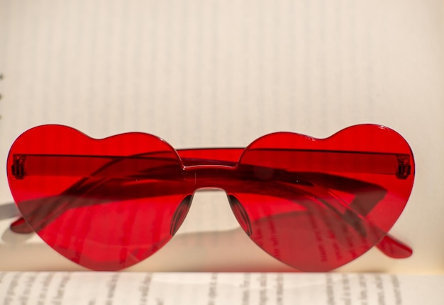 Rote herzförmige Brille auf einem Buch