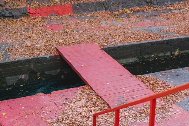 Rote Holzbrücke durch Betonwehr über den Fluss Fluss im Beton Revitalisiert