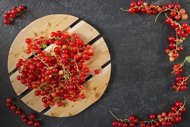 Rote Johannisbeerbeeren, die auf Grau mit Kopienraum liegen.