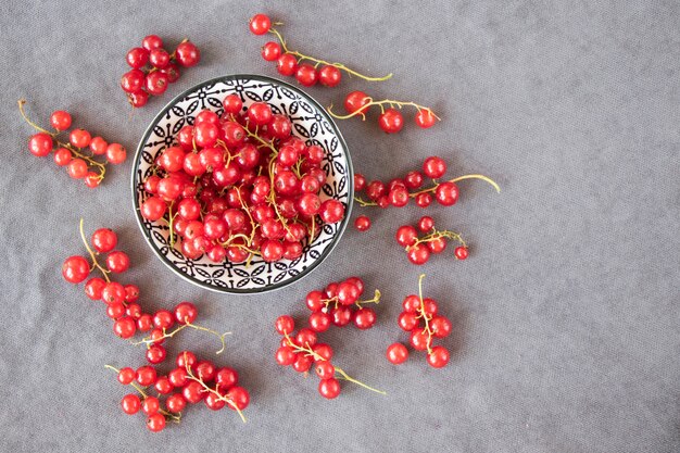 Rote Johannisbeere auf dem grauen Stoffhintergrund. Große Gruppe von bunten Beeren.