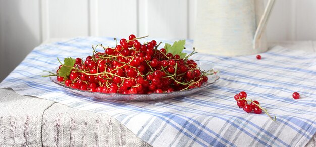 Rote Johannisbeeren in einer Glasplatte auf dem Tisch reife Beeren