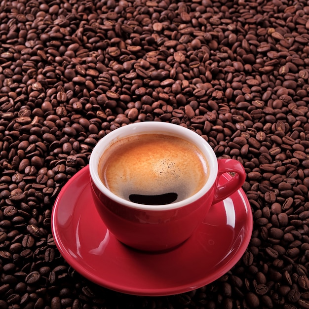 Rote Kaffeetasse mit Espresso und gerösteten Bohnen