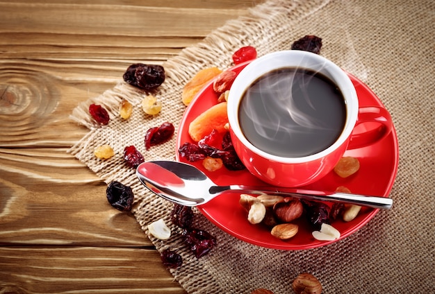 Rote keramische Schale mit heißem Kaffee auf hölzernen Brettern.