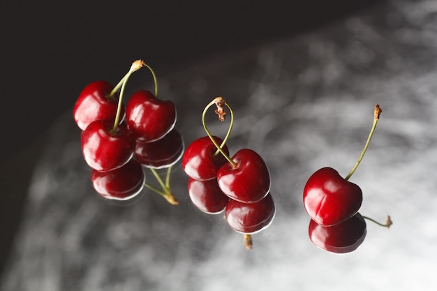 Rote Kirschen auf grauem Hintergrund mit Reflektion Frische Kirschen auf schwarzem Hintergrund