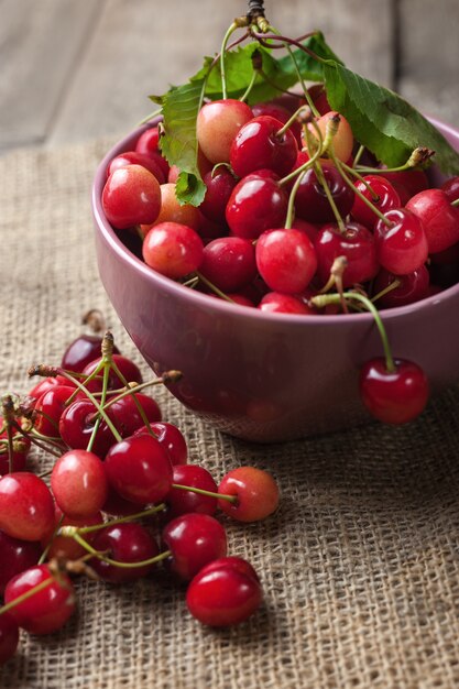 Rote Kirschen in der rosa Schüssel auf hölzernem