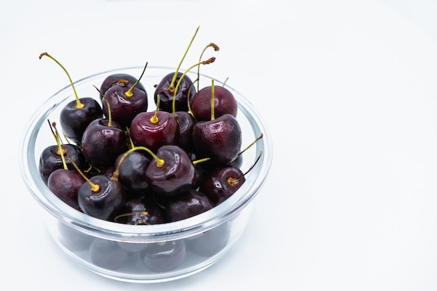 Rote Kirschfrucht in der Glasschüssel auf weißem Hintergrund.