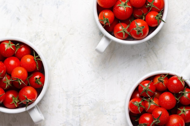 Rote Kirschtomaten in weißen Schalen auf hellgrauem Hintergrund