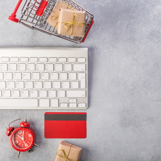 Rote Kreditkarte, Tastatur und Weihnachtsgeschenke auf grauer Tabellenebenenlage, Kopienraum.