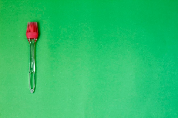 Rote Küchensilikonbürste auf grünem Hintergrund