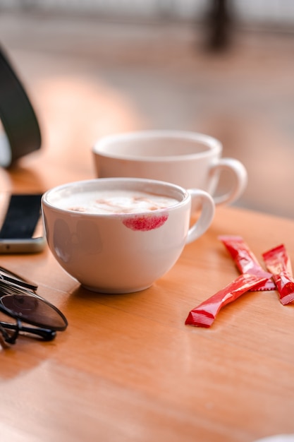 Rote Lippenstiftmarkierung auf einer Kaffeetasse auf dem Tisch im Café