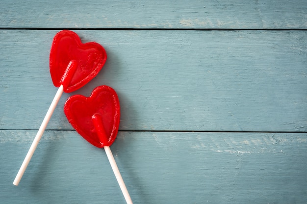 Rote Lutscher mit Herzform auf blauer Holzoberfläche lieben Konzept Valentinstag.