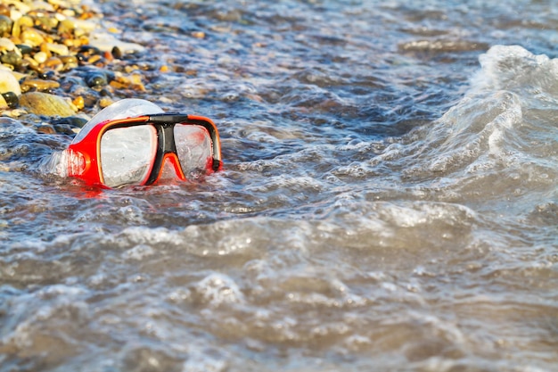 Rote Maske zum Tauchen am Kieselstrand