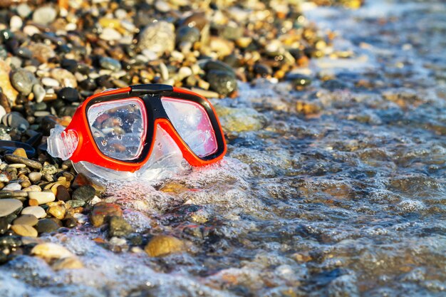 Rote Maske zum Tauchen am Kieselstrand