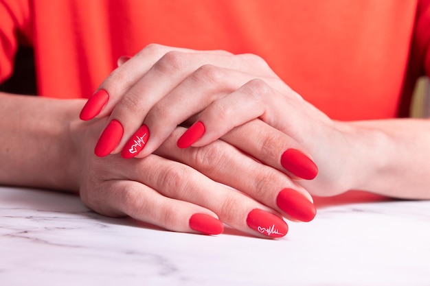 Rote matte Maniküre auf weiblichen Händen zum Valentinstag