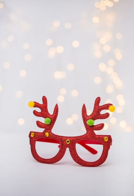 Rote Neujahrsbrille mit Hirschgeweih auf weißem Hintergrund mit Bokeh