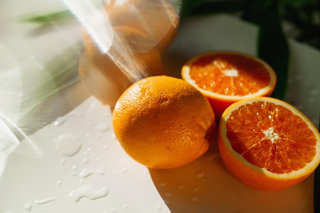 Rote Orangen Echtes lebendes Vitamin C Sie liegen auf einem weißen Tisch Lange grüne Blätter