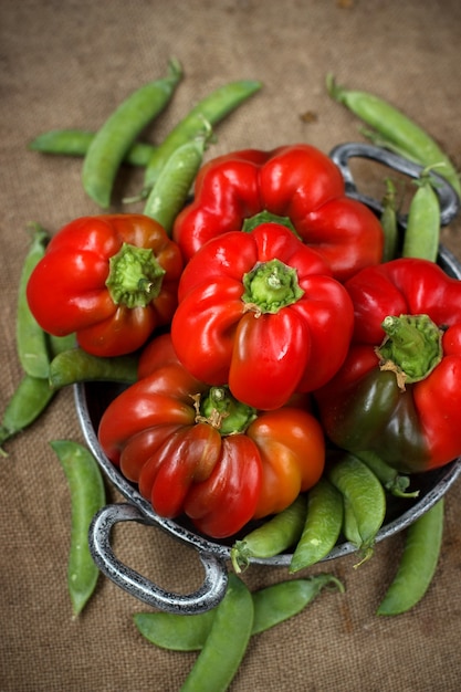 Rote Paprika in einer Metallplatte mit grünen Erbsen auf einem Tisch