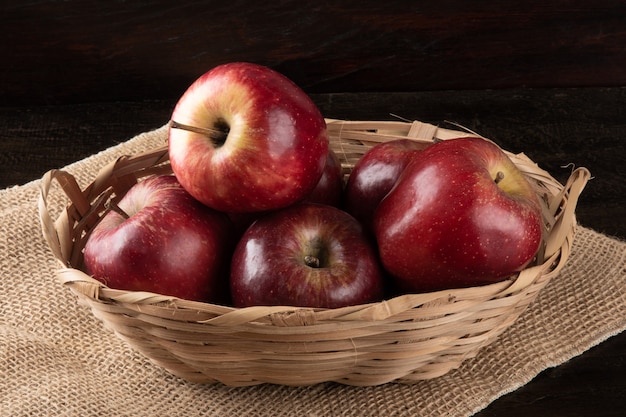 Rote Äpfel im Korb mit Holz.