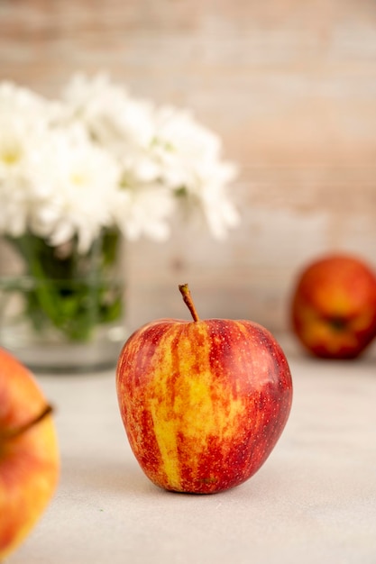 Rote Äpfel in der Schüssel auf hölzernem rustikalem Hintergrund Frische rote Apfelfrüchte mit Blumen