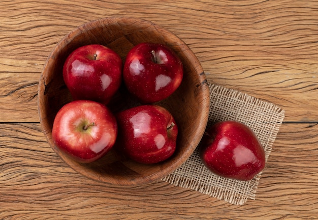 Rote Äpfel in einer Schüssel über Holztisch.