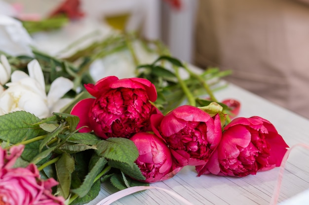 Rote Pfingstrosen liegen auf dem Tisch im Blumenladen