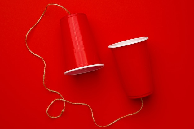 Rote Plastikbecher mit einem roten Faden verbunden