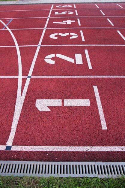 Foto rote rennstrecke auf der startlinie des stadions mit großen weißen zahlen