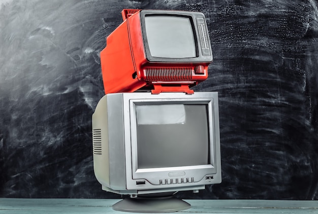 Rote retro tragbare Mini-Fernseher der alten Schule auf Tafelhintergrund