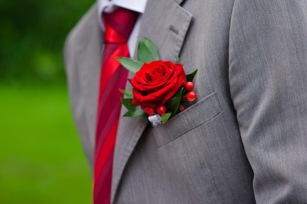 Rote Rose im Knopfloch auf grauem Anzug