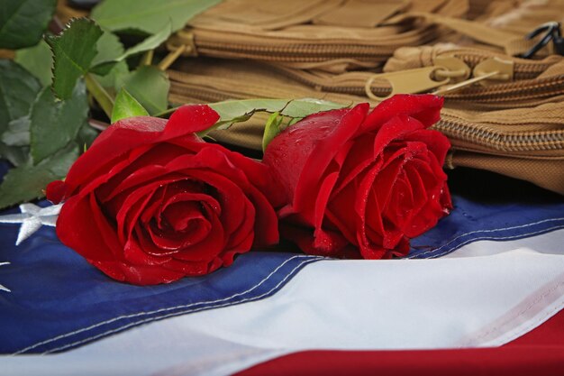 Rote Rosen auf amerikanischer Flagge mit Militärrucksack-Nahaufnahme