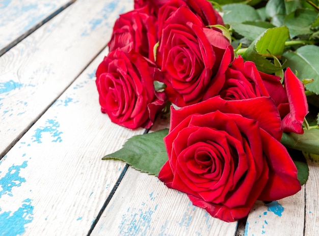 Rote Rosen auf einem alten blauen hölzernen Hintergrund