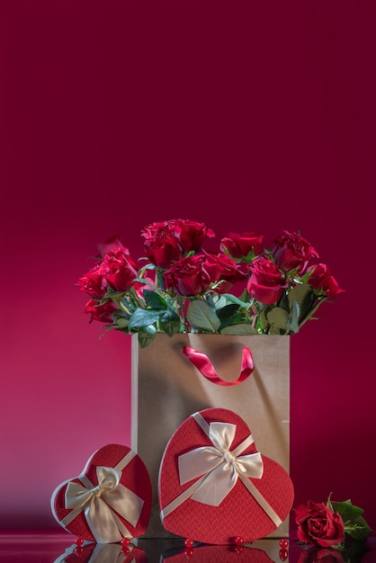 Rote Rosen in großer Basteltasche herzförmige Geschenkbox Rosenperlen auf einer Spiegelfläche