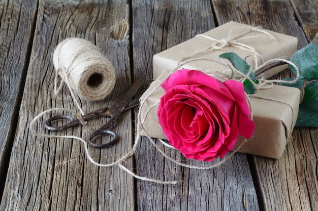 Rote Rosen und Geschenkbox auf einem Holz