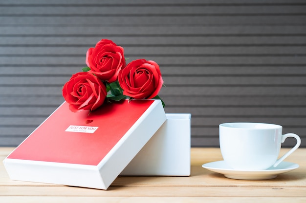 Rote Rosen und Geschenkbox auf Holz