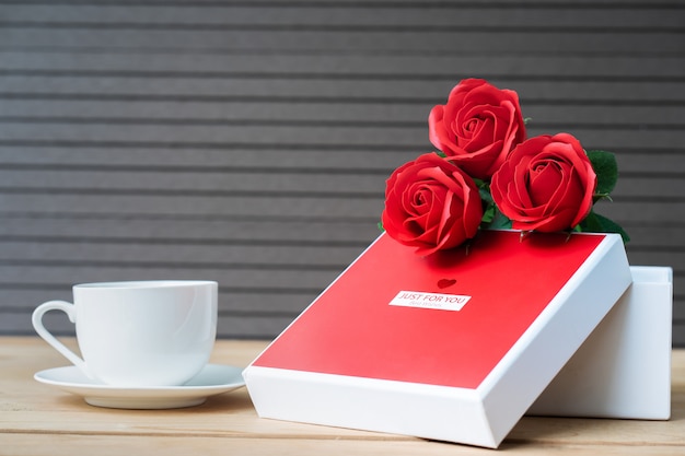 Rote Rosen und Geschenkbox auf Holztisch