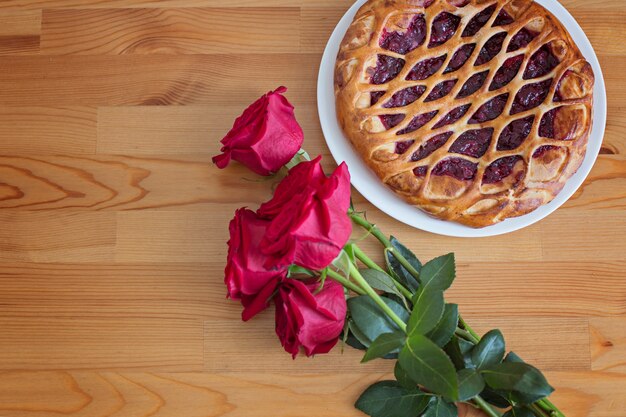 Rote Rosen und Kirschtorte auf einem Holztisch