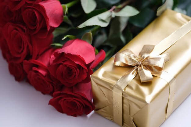 Rote Rosenblüten und Geschenkbox auf dem Tisch